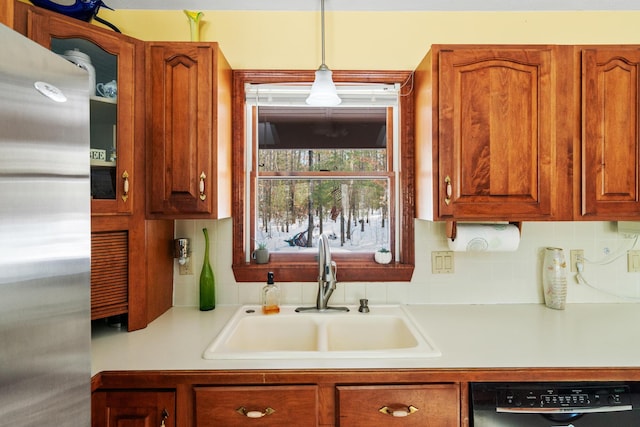 kitchen featuring stainless steel refrigerator, decorative light fixtures, black dishwasher, sink, and backsplash