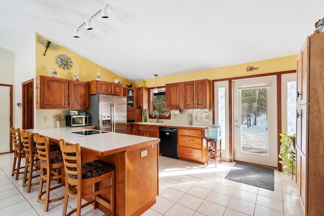 kitchen featuring a breakfast bar area, a wealth of natural light, black appliances, vaulted ceiling, and kitchen peninsula