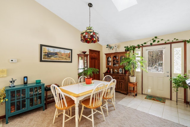 tiled dining space featuring vaulted ceiling with skylight