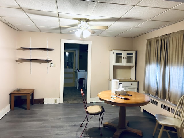 dining area featuring radiator heating unit, dark hardwood / wood-style floors, ceiling fan, and a paneled ceiling