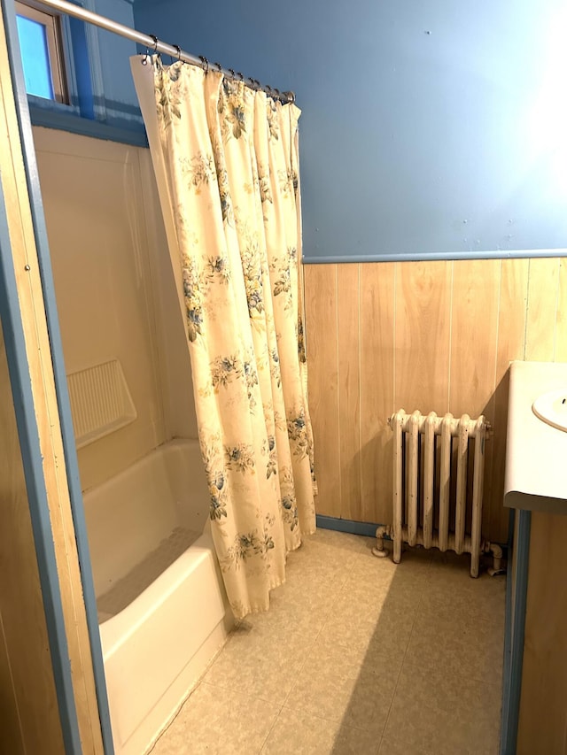 bathroom with shower / bath combination with curtain, vanity, wooden walls, and radiator