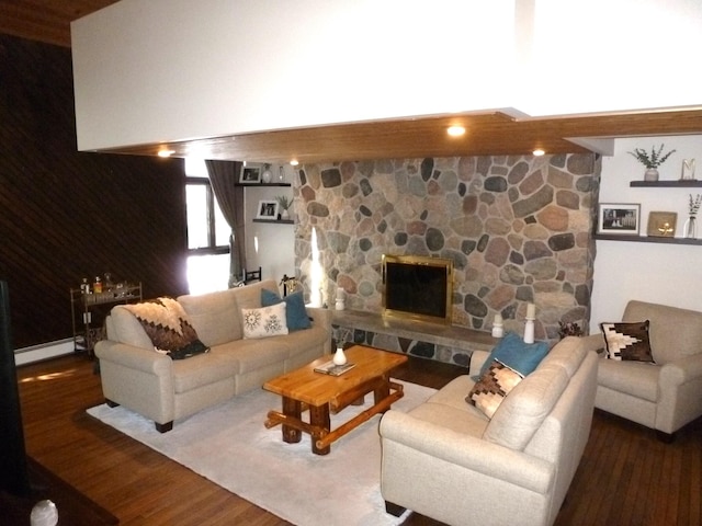 living room with a stone fireplace, baseboard heating, and hardwood / wood-style flooring