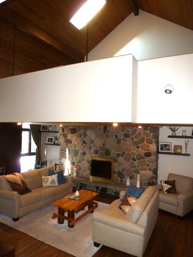 living room featuring beamed ceiling, wood-type flooring, a stone fireplace, and high vaulted ceiling