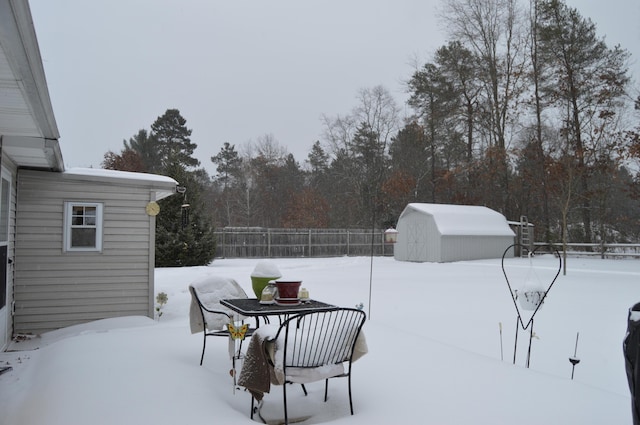 yard layered in snow featuring a shed