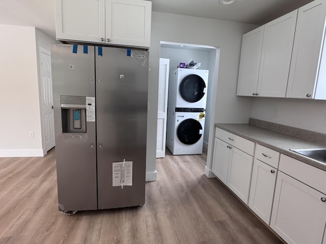 kitchen with stacked washer / dryer, white cabinets, and light hardwood / wood-style floors