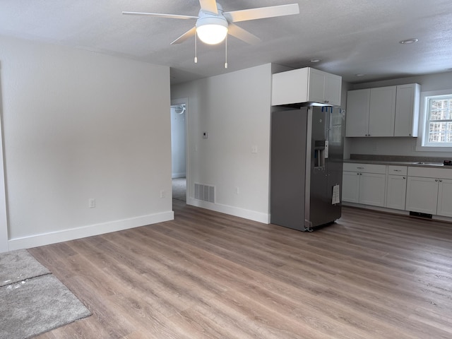 kitchen with white cabinets, stainless steel fridge, ceiling fan, a textured ceiling, and light hardwood / wood-style flooring