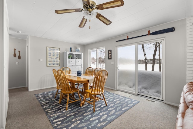 carpeted dining area featuring ceiling fan and a water view