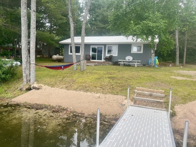 back of property featuring a water view and a lawn