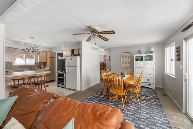 dining room with light carpet, sink, and ceiling fan with notable chandelier