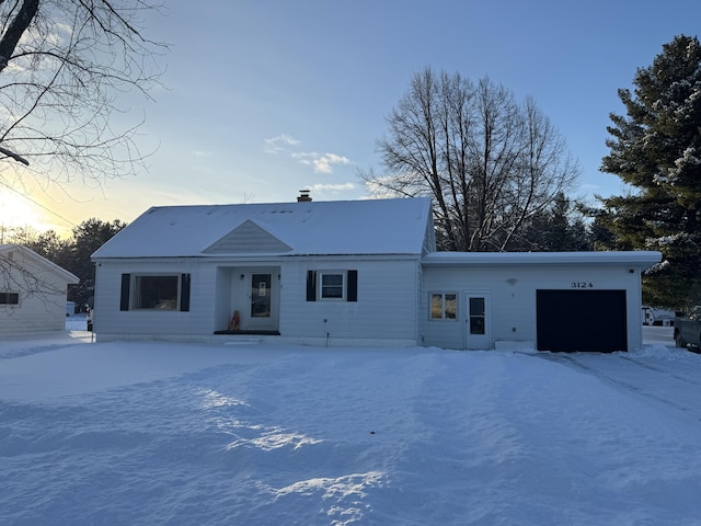 snow covered back of property featuring a garage