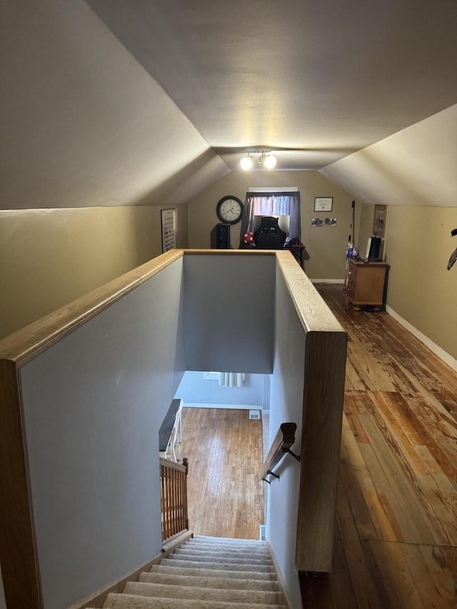 stairs featuring wood-type flooring and vaulted ceiling