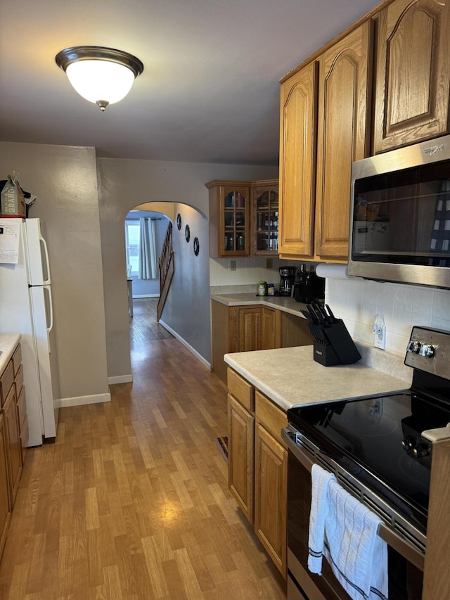 kitchen with decorative backsplash, appliances with stainless steel finishes, and light hardwood / wood-style flooring