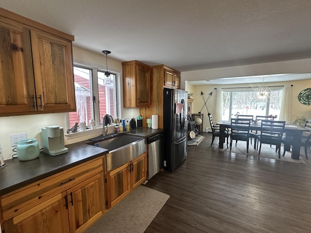 kitchen featuring pendant lighting, sink, dishwasher, black refrigerator, and dark hardwood / wood-style floors