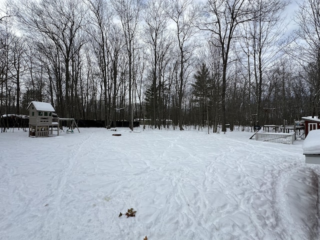 yard layered in snow featuring a playground