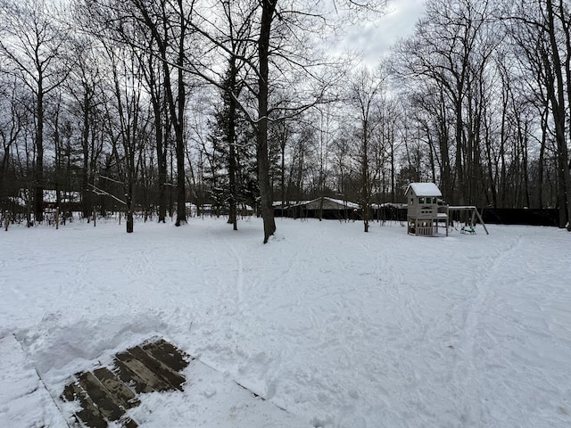 yard covered in snow featuring a playground