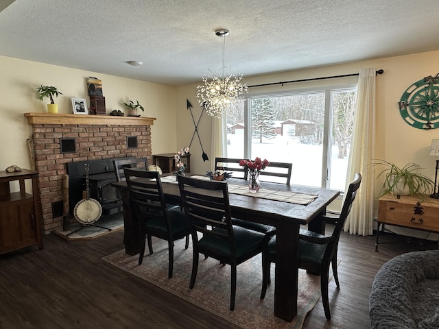 dining space with dark hardwood / wood-style flooring, a brick fireplace, a textured ceiling, and a chandelier