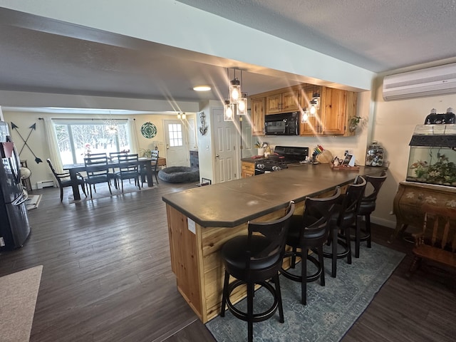 kitchen with pendant lighting, a breakfast bar, black appliances, dark hardwood / wood-style flooring, and an AC wall unit