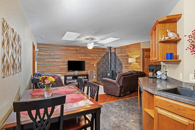 dining space with a skylight, sink, a textured ceiling, and a wood stove