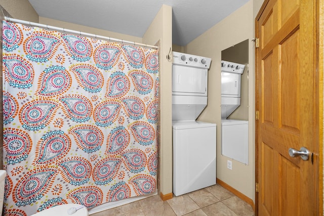 clothes washing area with light tile patterned flooring, stacked washer / drying machine, and a textured ceiling