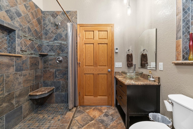 bathroom featuring vanity, tiled shower, and toilet