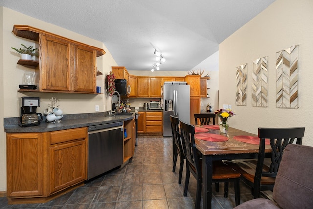 kitchen with stainless steel appliances, dark tile patterned floors, track lighting, and a textured ceiling