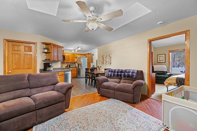 living room featuring ceiling fan, a textured ceiling, and light wood-type flooring