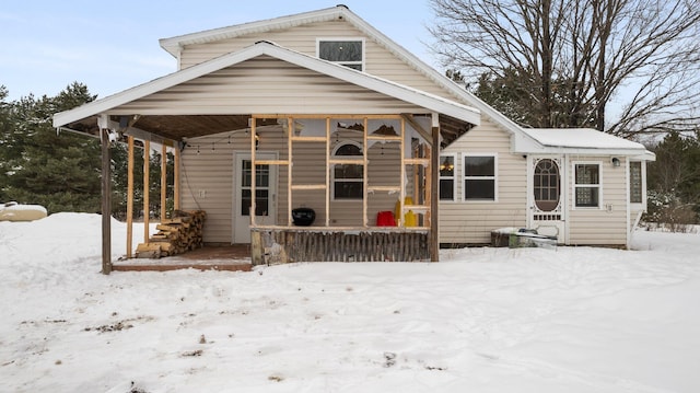 snow covered back of property featuring covered porch