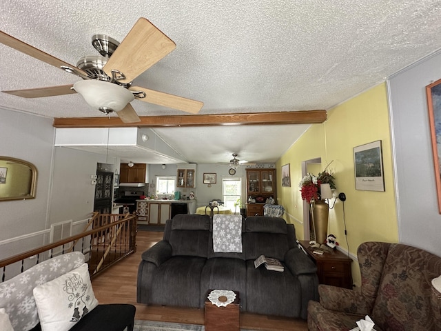 living room featuring ceiling fan, wood-type flooring, lofted ceiling with beams, and a textured ceiling