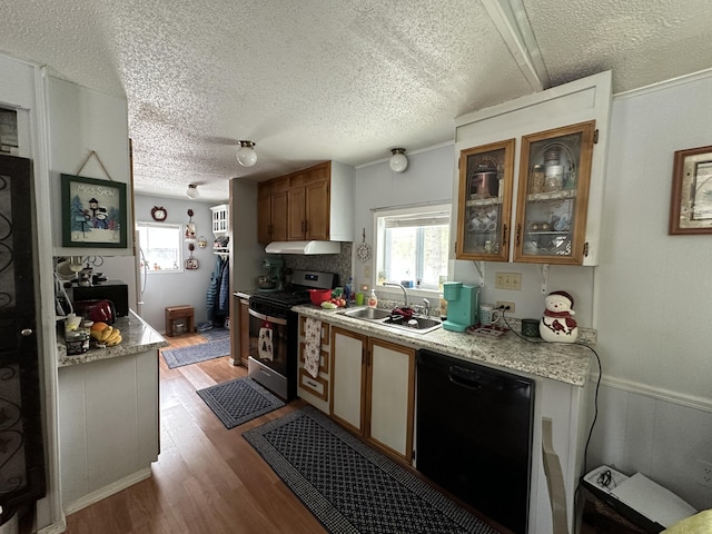 kitchen with black dishwasher, sink, light hardwood / wood-style floors, stainless steel gas range oven, and a textured ceiling