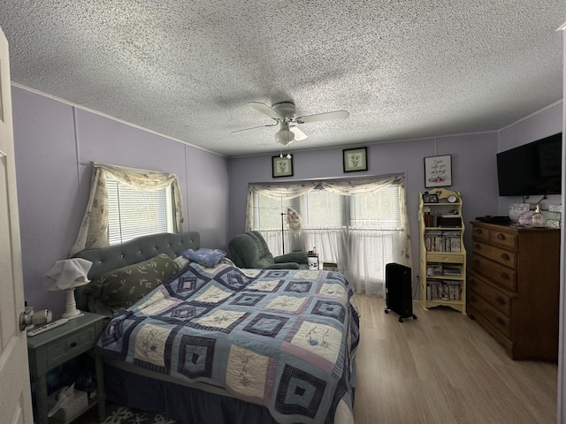 bedroom featuring a textured ceiling, ornamental molding, light hardwood / wood-style floors, and ceiling fan