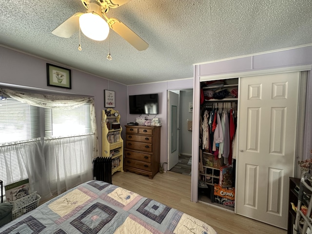 bedroom featuring vaulted ceiling, a textured ceiling, a closet, ceiling fan, and light hardwood / wood-style floors