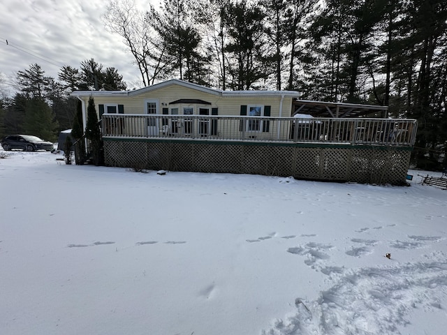 snow covered back of property with a wooden deck