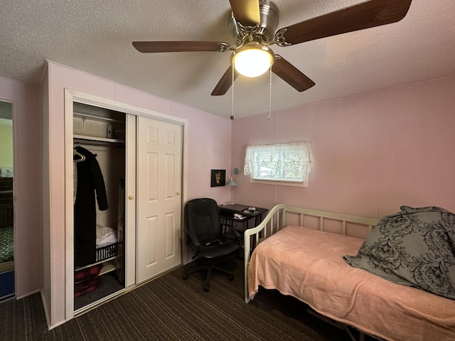 bedroom with ceiling fan, a closet, a textured ceiling, and dark colored carpet