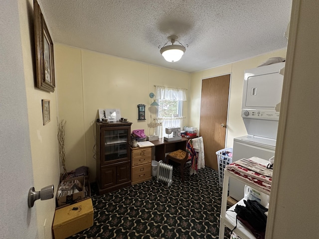 carpeted office space with stacked washer and clothes dryer and a textured ceiling