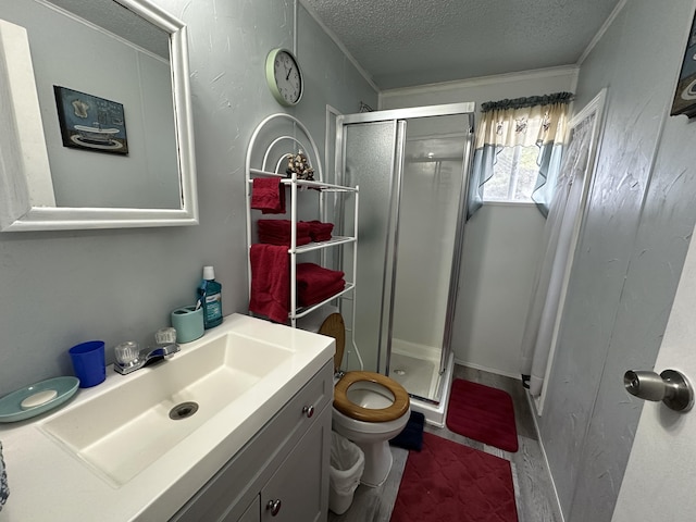 bathroom featuring vanity, toilet, an enclosed shower, and a textured ceiling