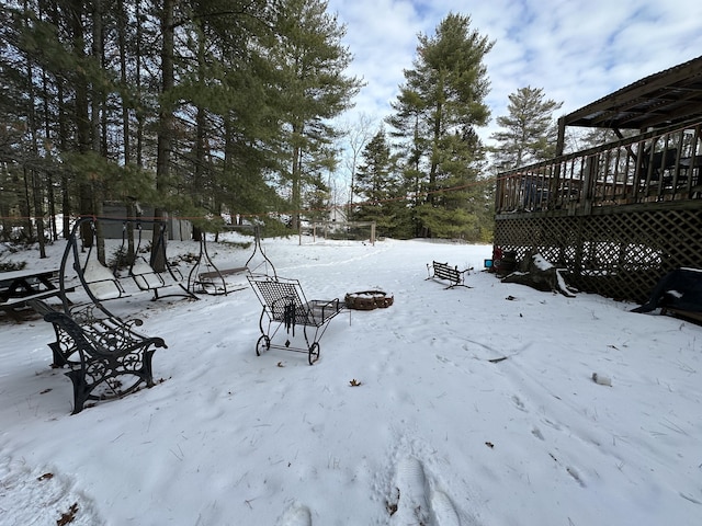 snowy yard with a deck and a fire pit