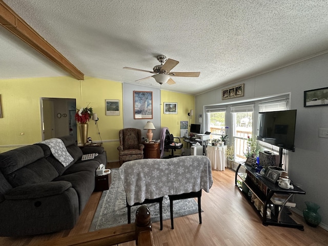 living room featuring vaulted ceiling with beams, a textured ceiling, ceiling fan, and light wood-type flooring