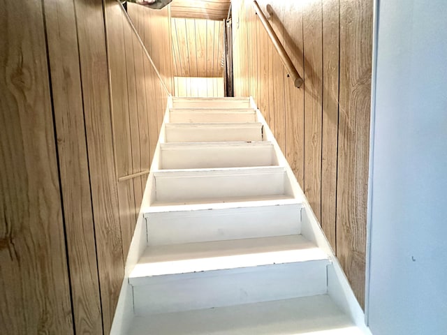 stairs featuring wood walls