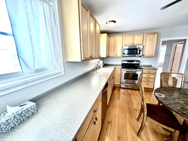 kitchen featuring appliances with stainless steel finishes, sink, light brown cabinetry, and light hardwood / wood-style floors