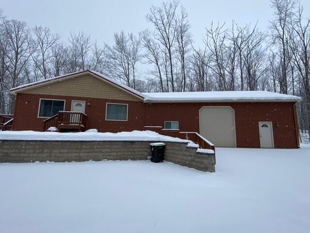 snow covered rear of property with a garage