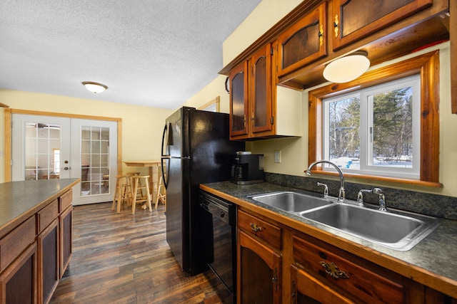 kitchen with black dishwasher, sink, dark hardwood / wood-style flooring, a textured ceiling, and french doors