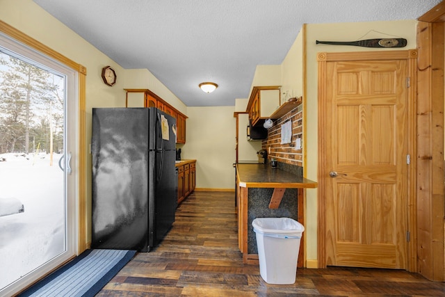 kitchen featuring black refrigerator, a textured ceiling, and dark hardwood / wood-style floors