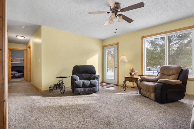 carpeted living room featuring ceiling fan and a textured ceiling