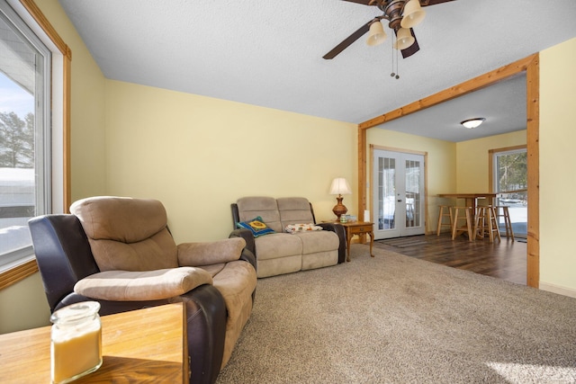 living room with french doors, ceiling fan, and dark colored carpet