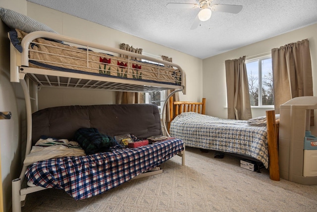 bedroom with ceiling fan, carpet floors, and a textured ceiling