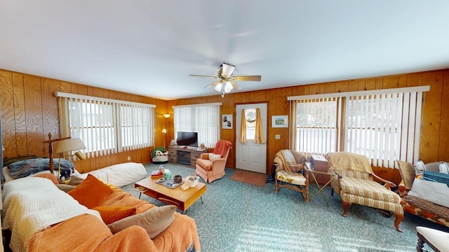 carpeted living room with plenty of natural light, wooden walls, and ceiling fan