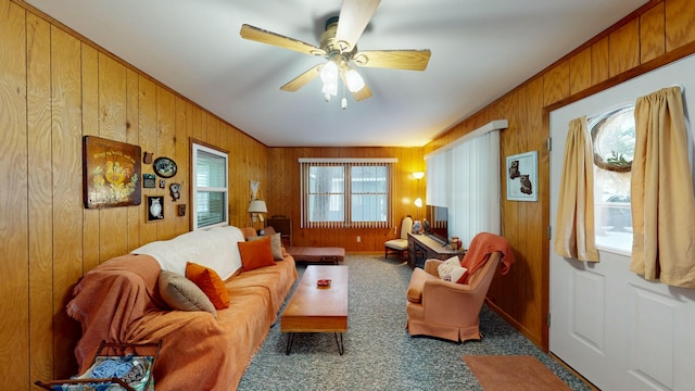 carpeted living room with ceiling fan and wooden walls