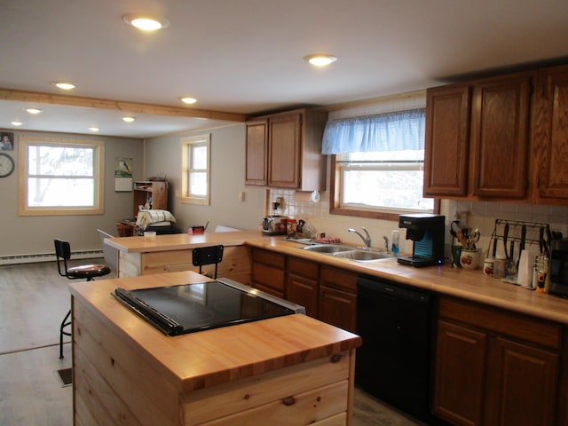 kitchen with a wealth of natural light, sink, butcher block countertops, black appliances, and tasteful backsplash