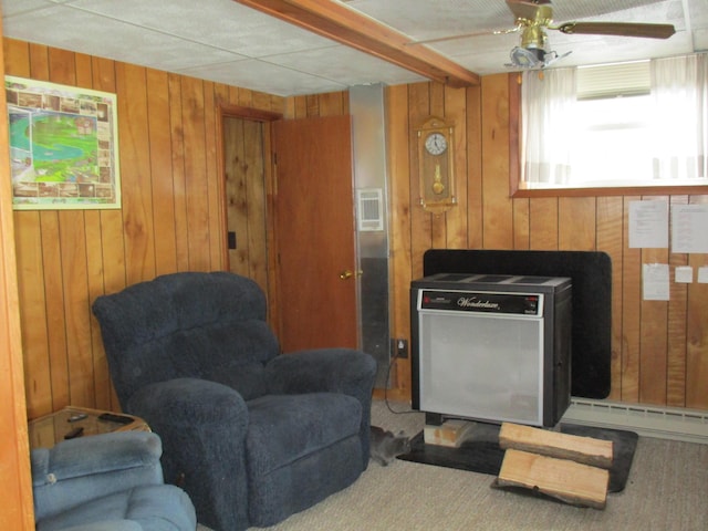 living area with heating unit, wooden walls, and ceiling fan