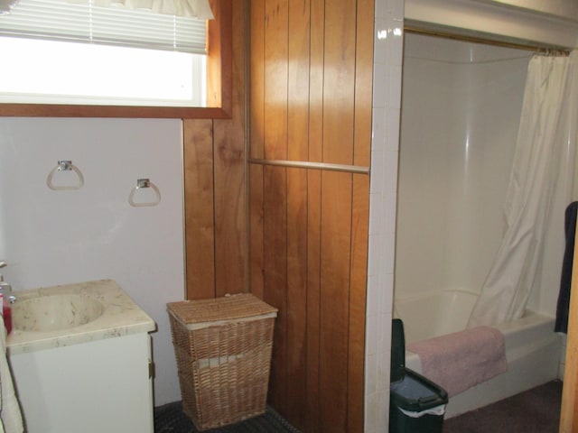 bathroom with vanity, shower / bathtub combination with curtain, and wooden walls